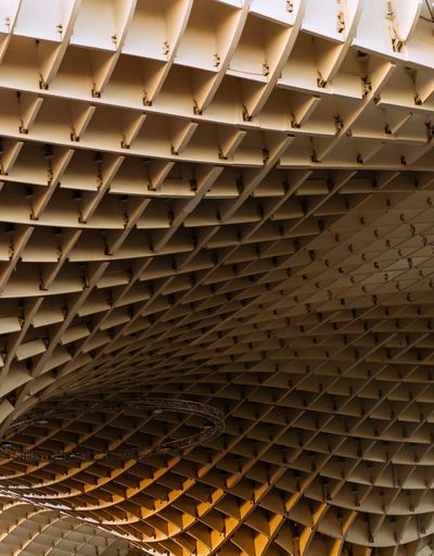 Underside of Seville’s Metropol Parasol, showing the intersecting lattice of its timber canopy.